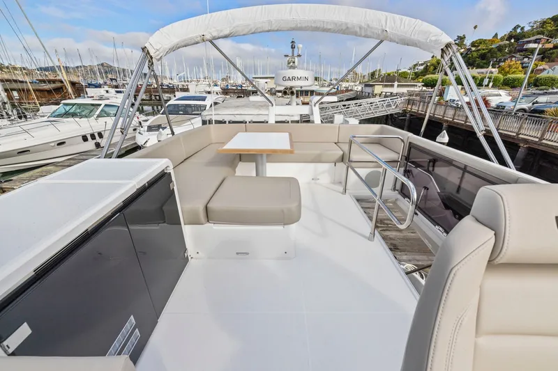 Slide: The Image of Flybridge of 2025 Fairline Squadron 50 yacht with seating and table, docked at marina. - 100