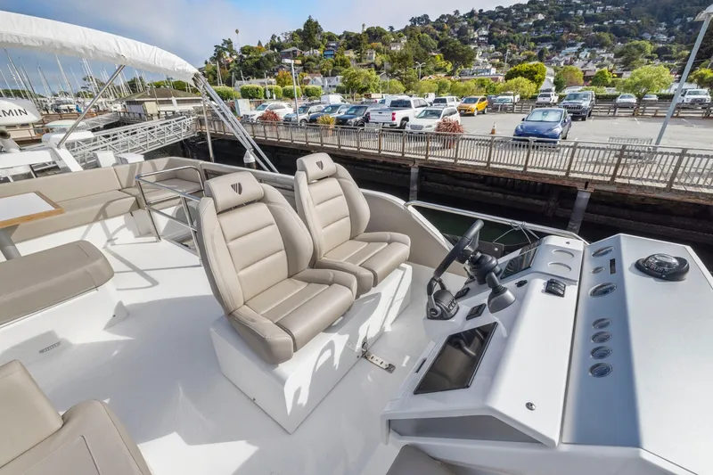 Slide: The Image of 2025 Fairline Squadron 50 yacht helm with luxurious seating and modern controls, docked at marina. - 95