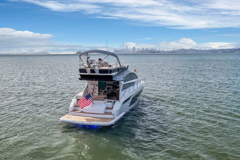 Slide: The Image of 2025 Fairline Squadron 50 yacht cruising on open water with city skyline in background. - 47