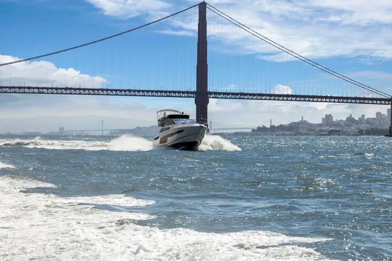 Slide: The Image of 2025 Fairline Squadron 50 yacht cruising under a large suspension bridge on a sunny day. - 36