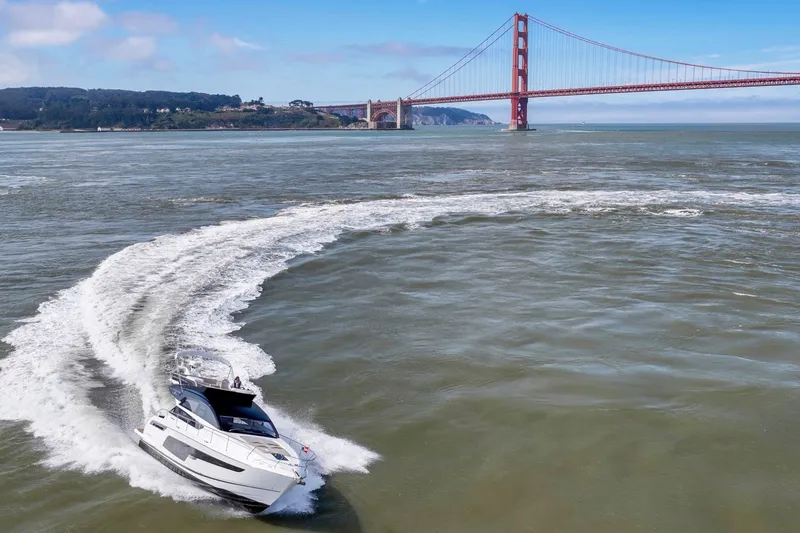 Slide: The Image of 2025 Fairline Squadron 50 yacht cruising near iconic red suspension bridge. - 13