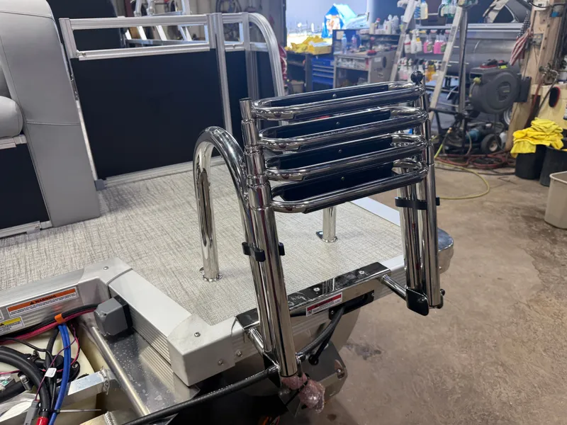 Slide: The Image of A stainless steel swim ladder is mounted at the rear of a boat, surrounded by workshop items. - 40