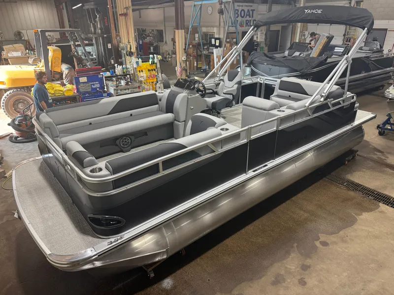 The Image of A modern pontoon boat with gray upholstery and a black hull, parked in a workshop. - 1