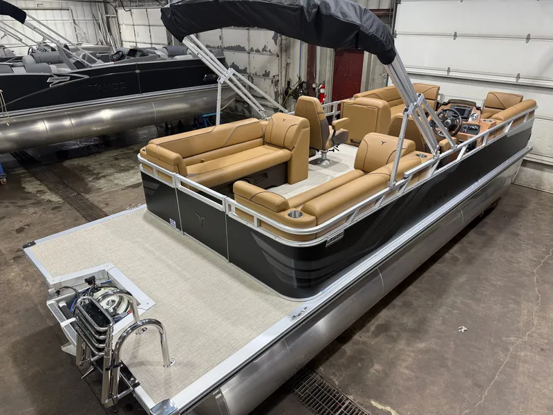 Slide: The Image of A modern pontoon boat with beige seating and a black canopy, parked in a warehouse. - 45