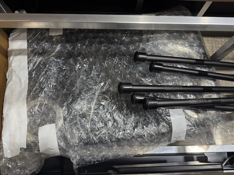 Slide: The Image of A boat part wrapped in bubble wrap, with several black rods beside it. - 42