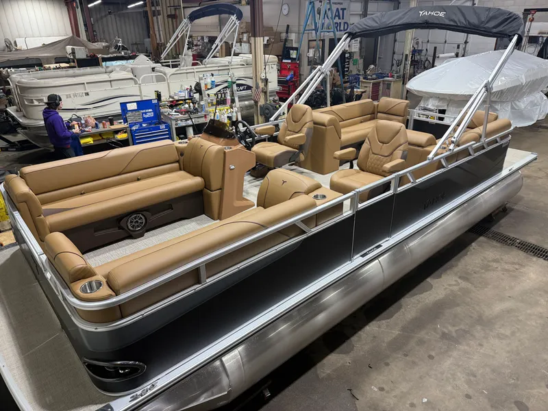 The Image of A modern pontoon boat with beige leather seating and a black canopy, inside a warehouse. - 1