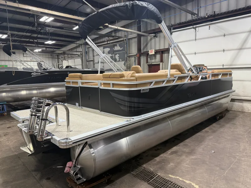 Slide: The Image of A modern pontoon boat with a black hull and beige interior is in a warehouse. - 39