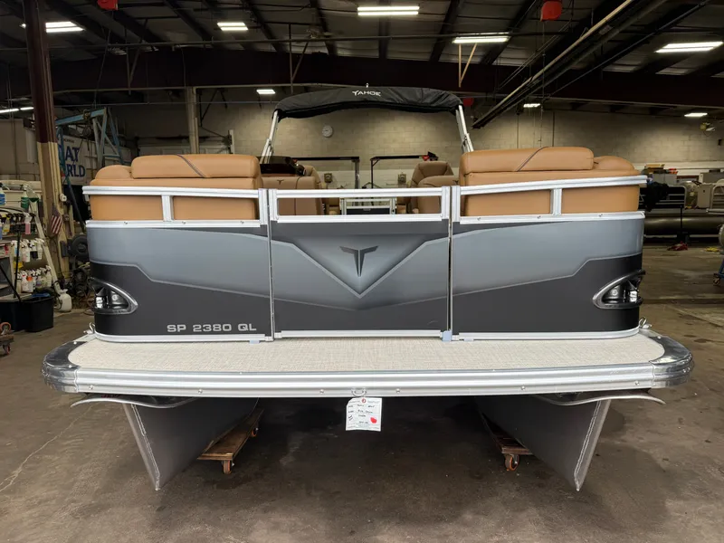 Slide: The Image of A gray pontoon boat with brown seating is in a warehouse. - 30