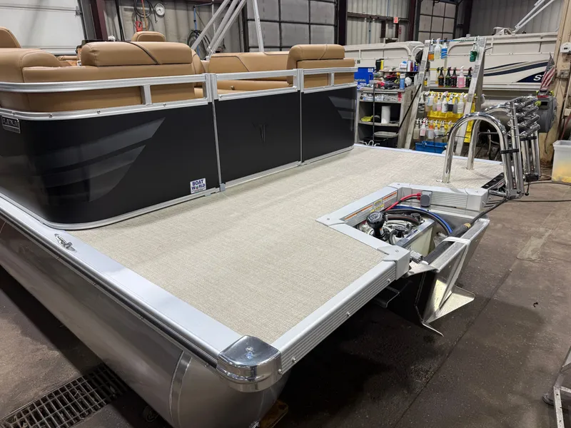 Slide: The Image of A modern pontoon boat with a beige deck and tan seats, parked in a workshop. - 35
