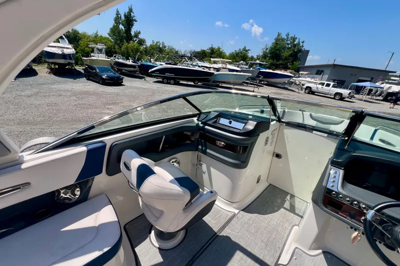 Slide: The Image of 2020 Chaparral 277 SSX boat interior with helm, seating, and dashboard in a marina setting. - 19