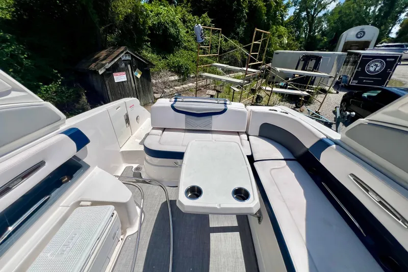 Slide: The Image of 2020 Chaparral 277 SSX boat interior with seating and table, surrounded by outdoor equipment. - 13