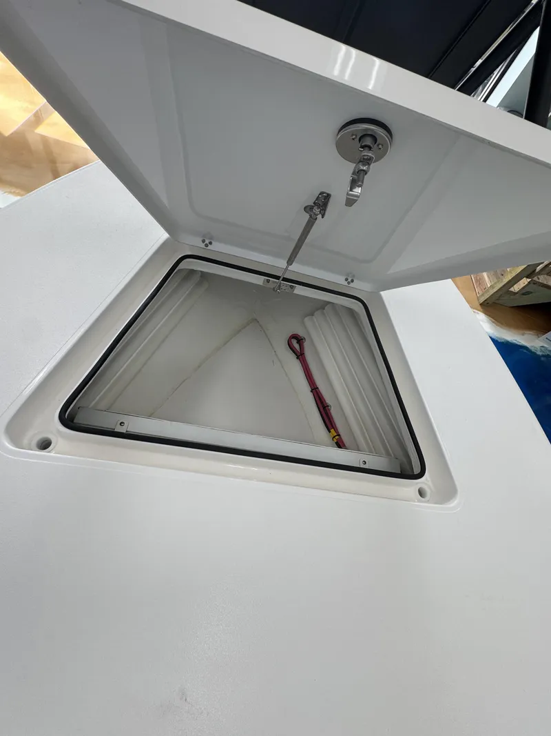 Slide: The Image of An open storage compartment on a 2027 Maverick 18 HPX-V boat, with a red tool inside. - 27