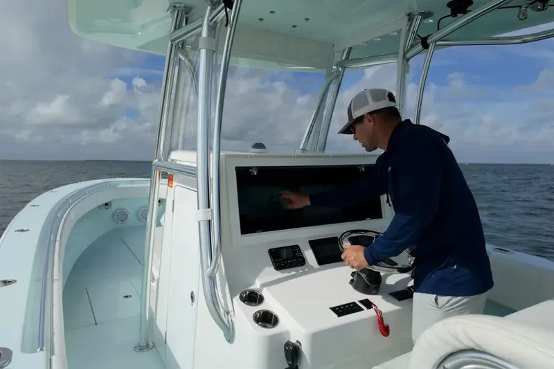 Slide: The Image of Man operating 2025 Contender 39 ST boat's control panel on open water. - 17