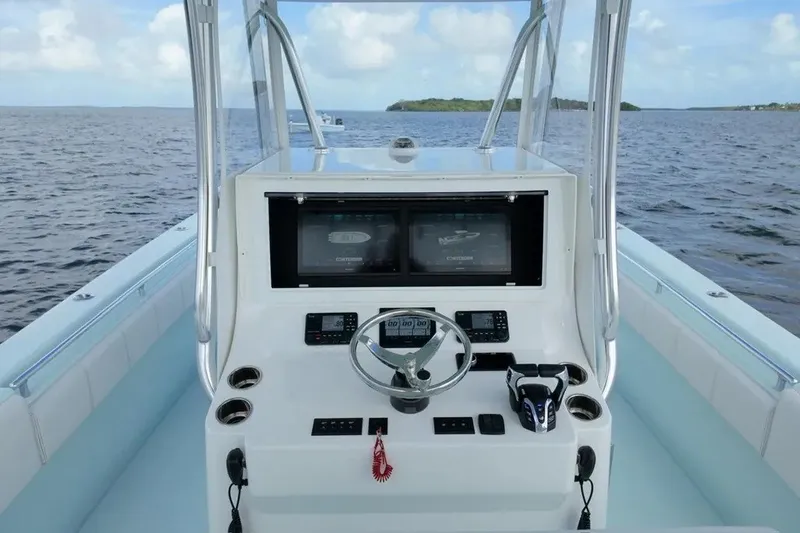 Slide: The Image of 2025 Contender 39 ST boat console with dual screens, steering wheel, and ocean view. - 14