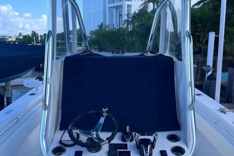 Slide: The Image of 2024 Contender 30 Tournament boat console with steering wheel and controls, docked near waterfront. - 20