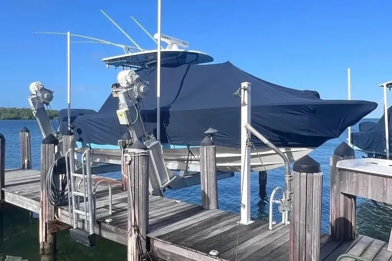 The Image of 2024 Contender 30 Tournament boat covered and docked on a lift by the water. - 1