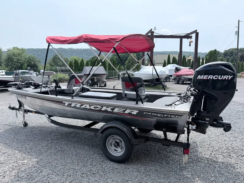 The Image of A 2016 Tracker Panfish 16 boat with a red sunshade and Mercury outboard motor on a trailer. - 1