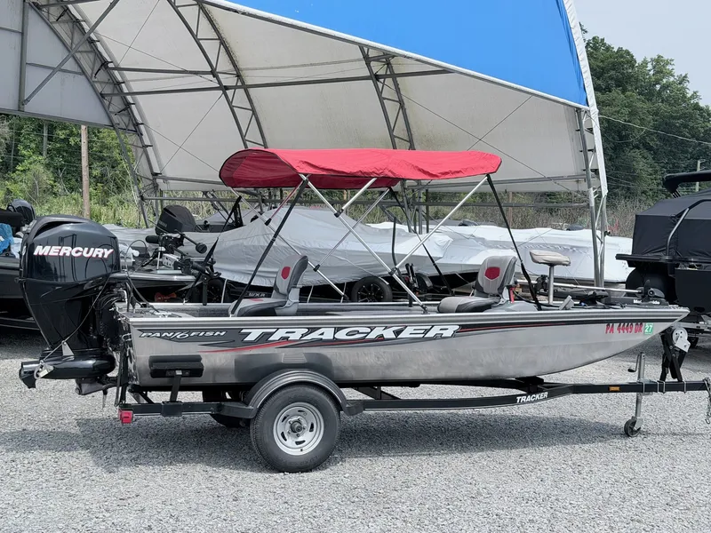 Slide: The Image of A 2016 Tracker Panfish 16 boat with a red canopy, parked on a trailer. - 17