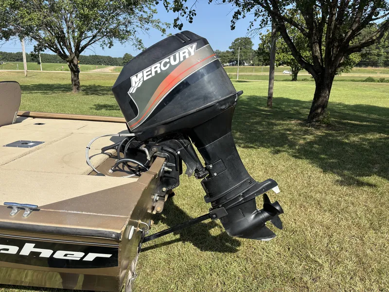 Slide: The Image of A Mercury outboard motor is mounted on a Fisher boat, situated on a grassy field. - 12