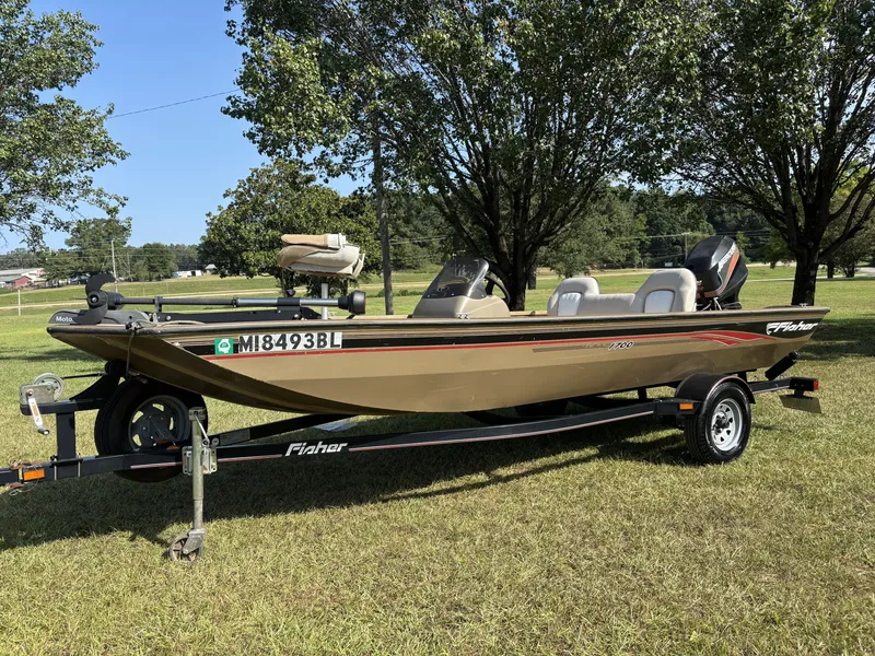 Slide: The Image of A 2006 Fisher Boats 1700 on a trailer, set on grass, surrounded by trees. - 3