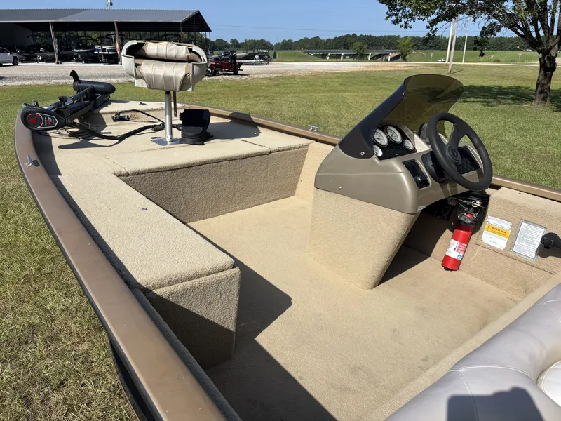 Slide: The Image of A 2006 Fisher Boats 1700 with beige interior, steering console, and fire extinguisher, parked on grass. - 6
