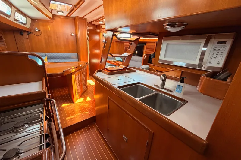 Slide: The Image of Luxurious 2005 Tayana 48 yacht interior with wooden cabinetry, modern kitchen, and cozy seating area. - 98