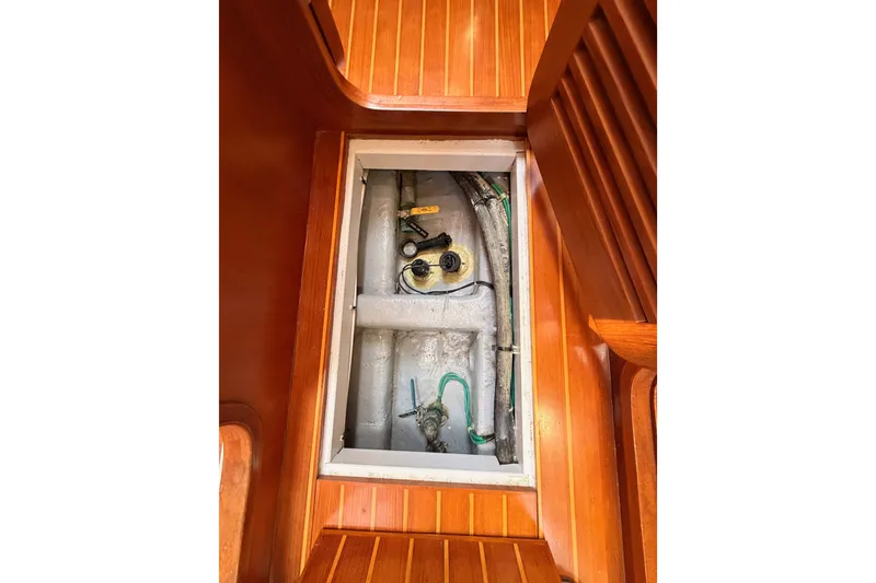 Slide: The Image of Access hatch in 2005 Tayana 48 sailboat, revealing interior components and wooden flooring. - 114