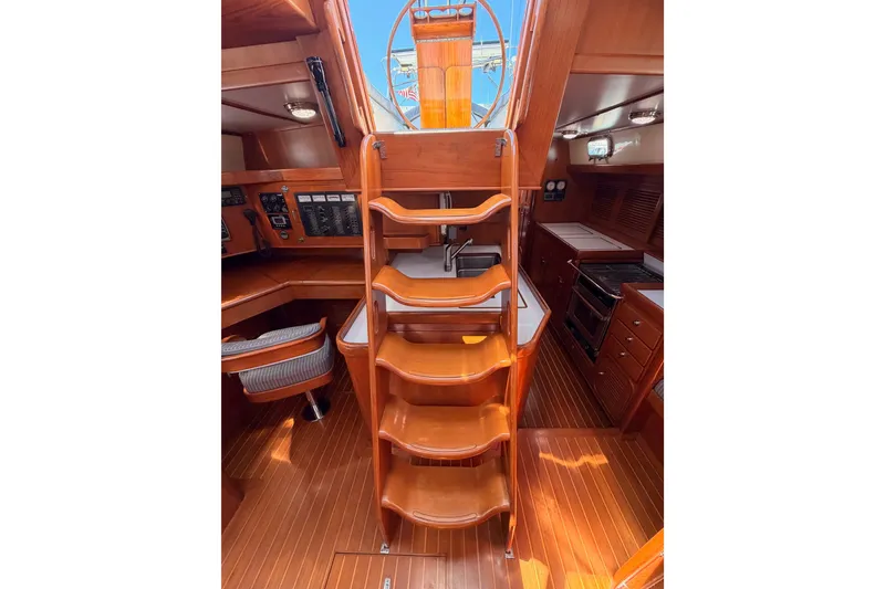 Slide: The Image of Interior of 2005 Tayana 48 yacht featuring wooden stairs, navigation area, and galley kitchen. - 100