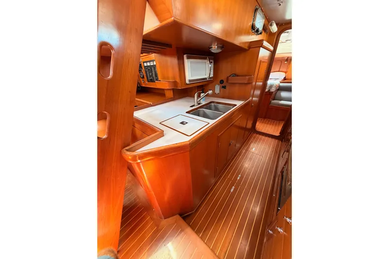 Slide: The Image of 2005 Tayana 48 yacht interior with wooden cabinetry, dual sinks, and microwave. - 77