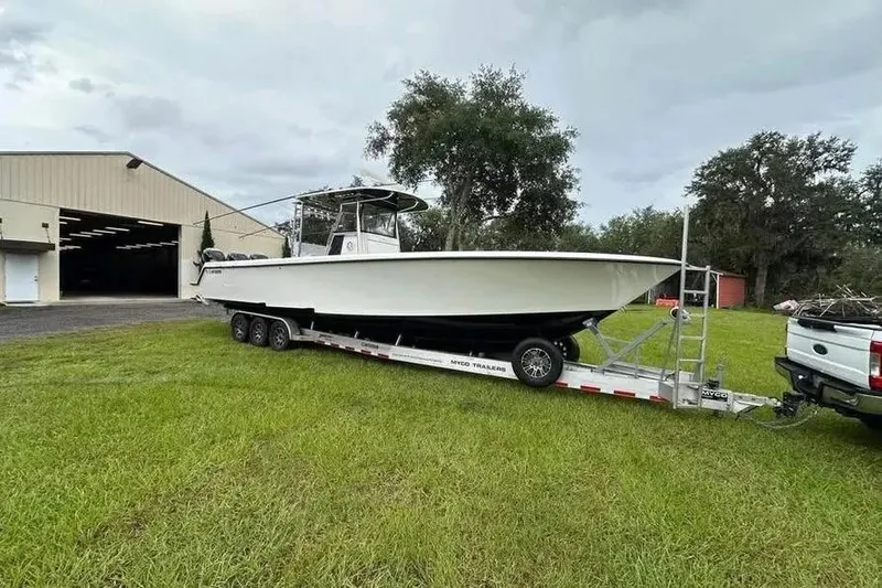 Slide: The Image of 2019 Contender 39 ST boat on trailer near a large warehouse, parked on grass. - 3