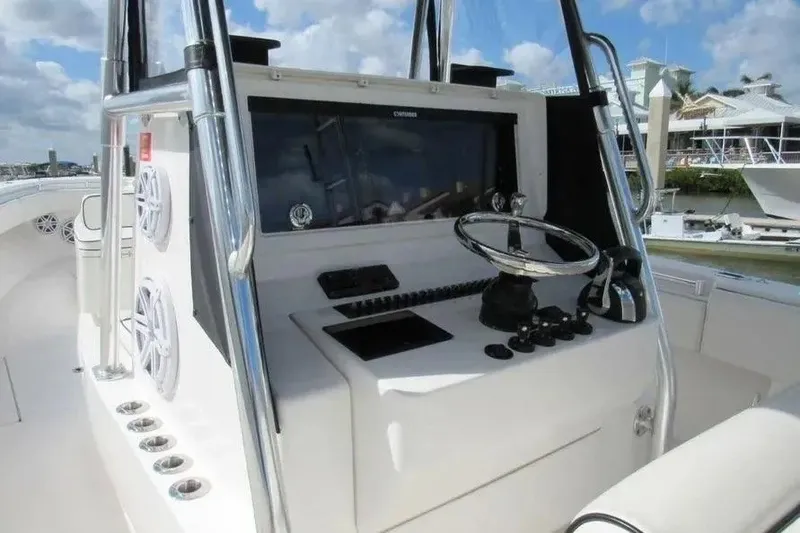 Slide: The Image of 2019 Contender 39 ST boat console with steering wheel and controls, docked under a blue sky. - 14