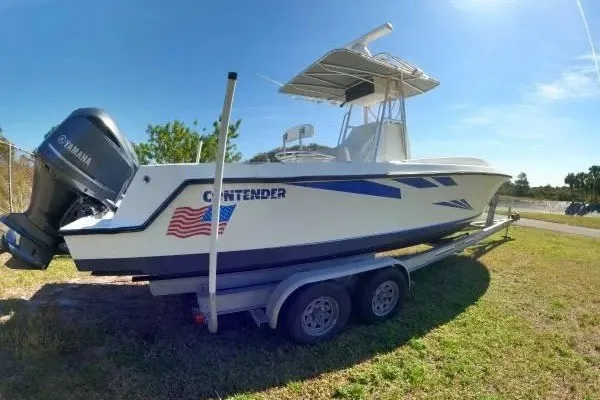 Slide: The Image of 1999 Contender 28 Sport boat on trailer with Yamaha outboard, parked on grass. - 3