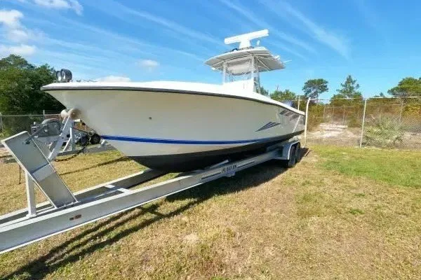 Slide: The Image of 1999 Contender 28 Sport boat on trailer, parked on grass under blue sky. - 14