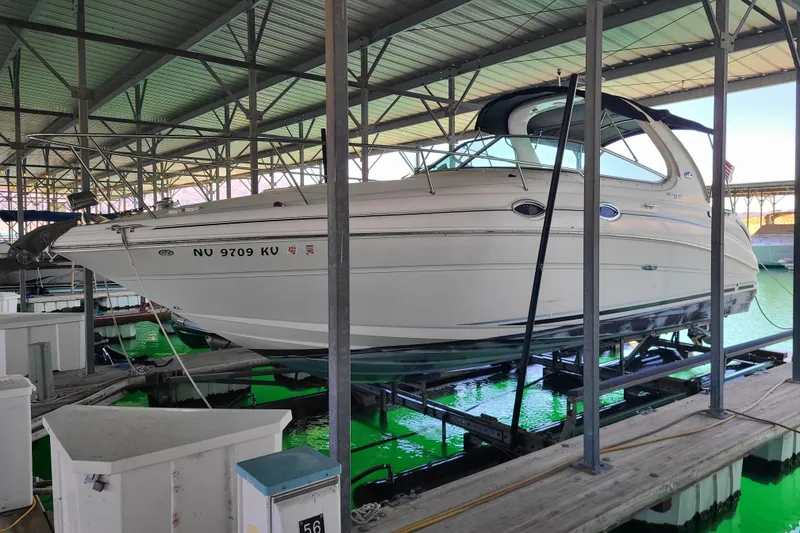 Slide: The Image of 2004 Sea Ray Sundancer 280 docked in a covered marina, showcasing sleek design. - 0