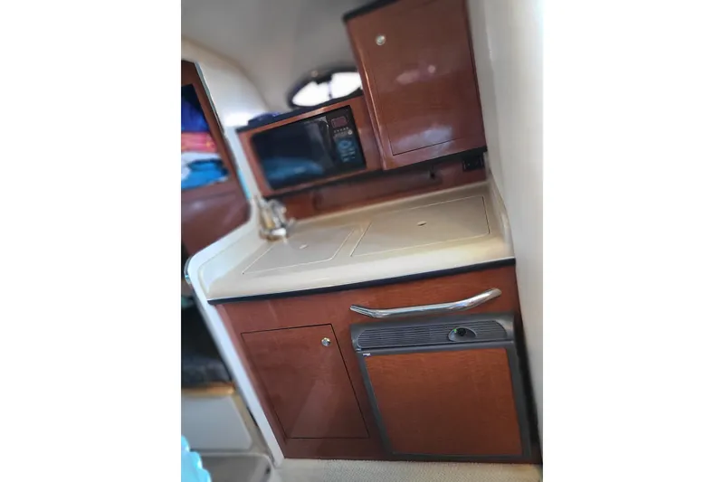 Slide: The Image of 2004 Sea Ray Sundancer 280 interior kitchenette with microwave, sink, and storage cabinets. - 5