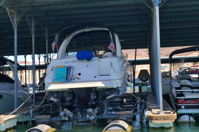 Slide: The Image of 2004 Sea Ray Sundancer 280 docked in a covered marina, rear view with flags. - 1