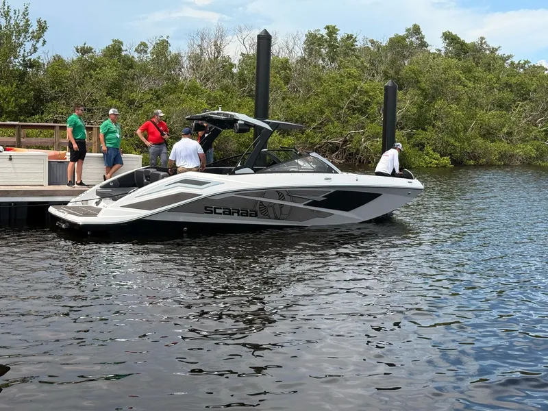 Slide: The Image of A 2026 Scarab 285 LX boat is docked. Several people are on board and on the shore. - 3