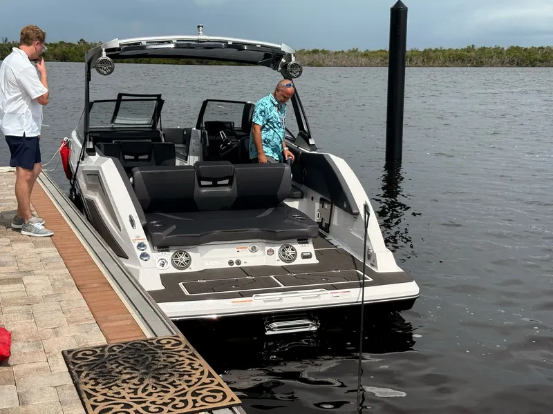Slide: The Image of A modern 2026 Scarab 285 LX docked at a pier. Two people are nearby. - 6
