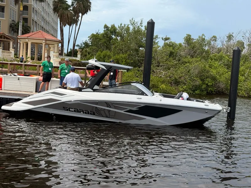 The Image of A 2026 Scarab 285 LX boat docked. It features a sleek design, white with black accents. - 1