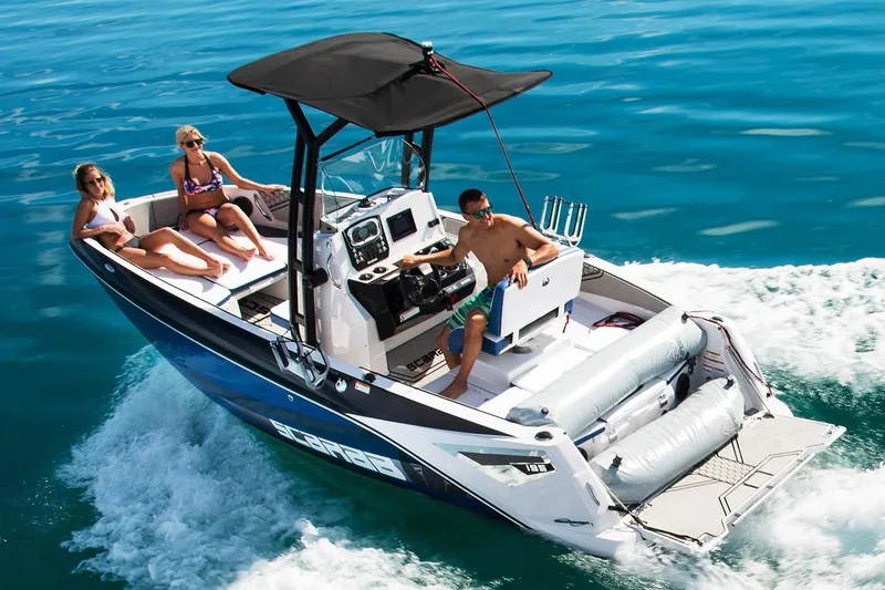 Slide: The Image of A 2019 Scarab 195 Open ID boat speeds across the water. Three people relax on board. - 8