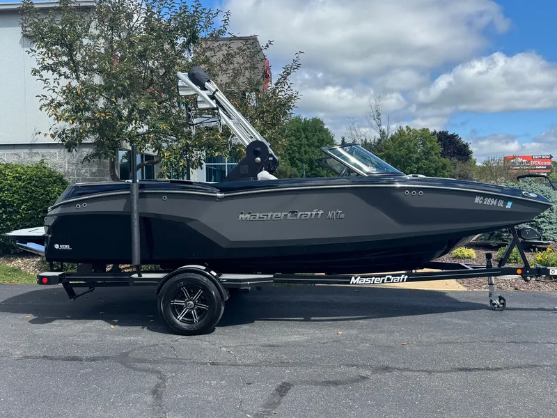 The Image of A black 2020 MasterCraft NXT20 boat is on a trailer outdoors. - 1