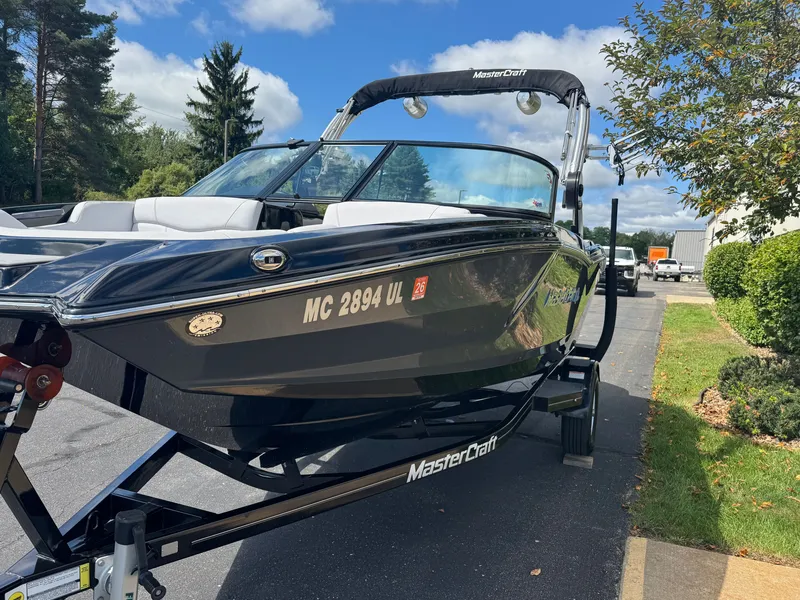Slide: The Image of A black 2020 MasterCraft NXT20 boat on a trailer in a sunny setting. - 4