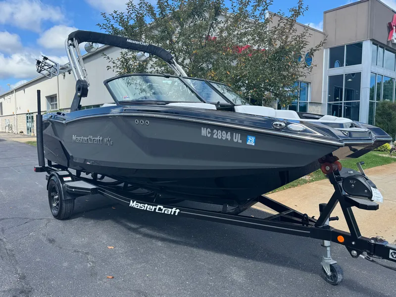 Slide: The Image of A 2020 MasterCraft NXT20 boat on a trailer in front of a building. - 2