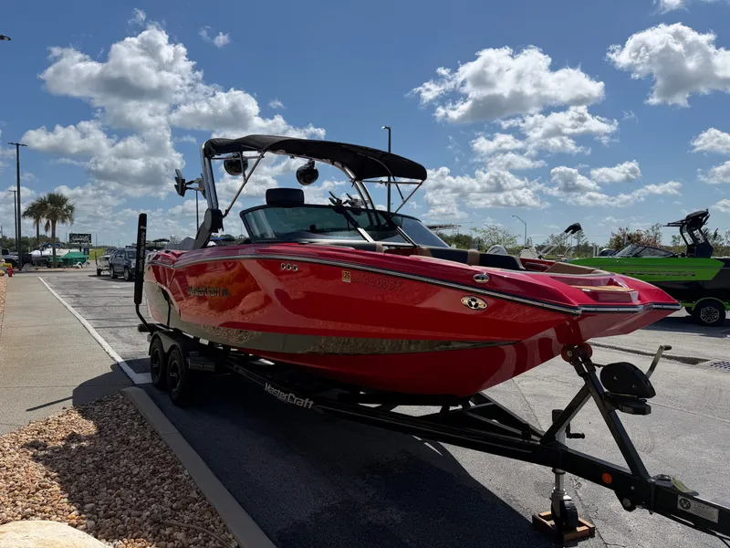Slide: The Image of A red 2022 MasterCraft NXT24 boat on a trailer under a sunny sky. - 4