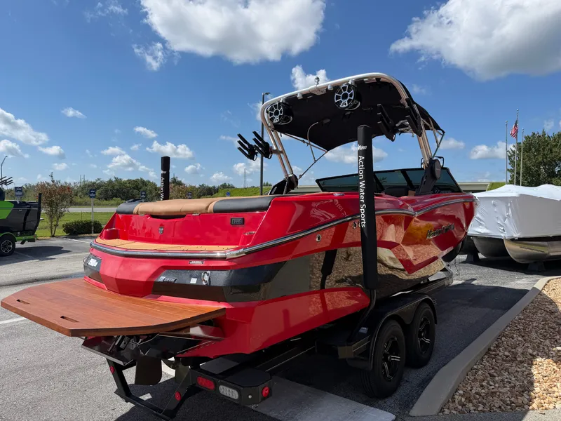 Slide: The Image of A red 2022 MasterCraft NXT24 boat on a trailer under a blue sky. - 5