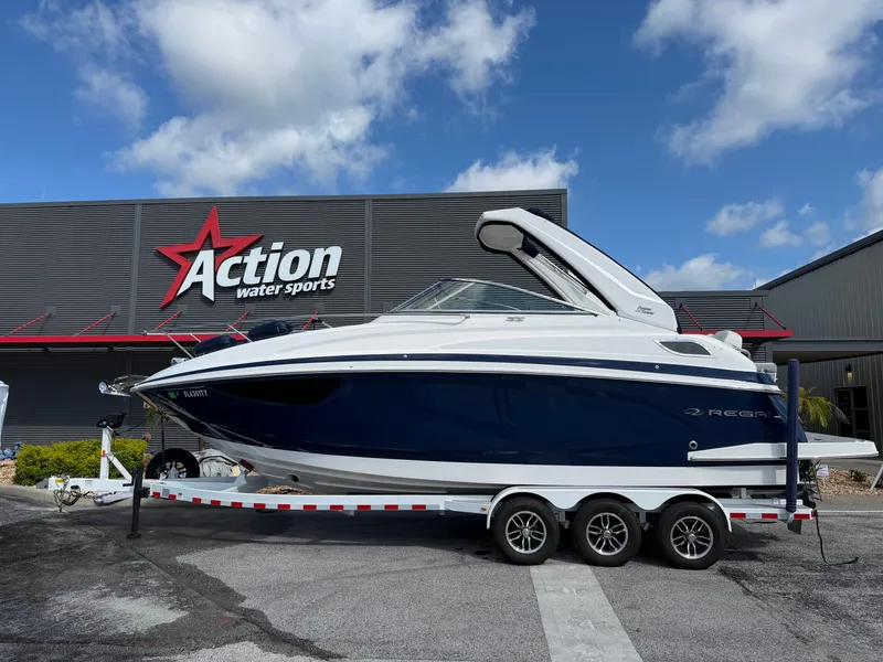 The Image of A 2023 Regal 28 Express boat on a trailer in front of a building labeled "Action Water Sports." - 1