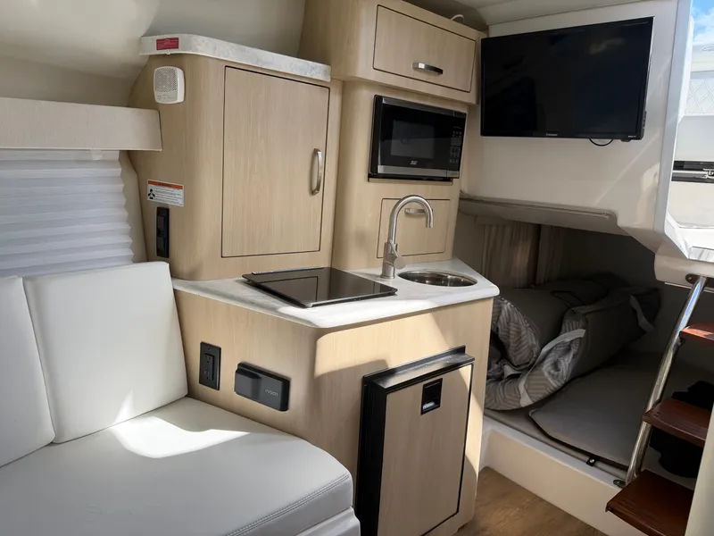 Slide: The Image of The interior of a 2023 Regal 28 Express features a compact kitchen with a microwave and sink. - 20
