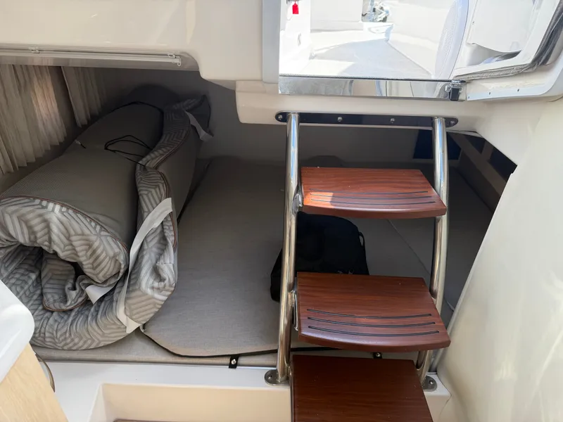 Slide: The Image of The cabin of the 2023 Regal 28 Express features a compact sleeping area with stacked wooden steps. - 21