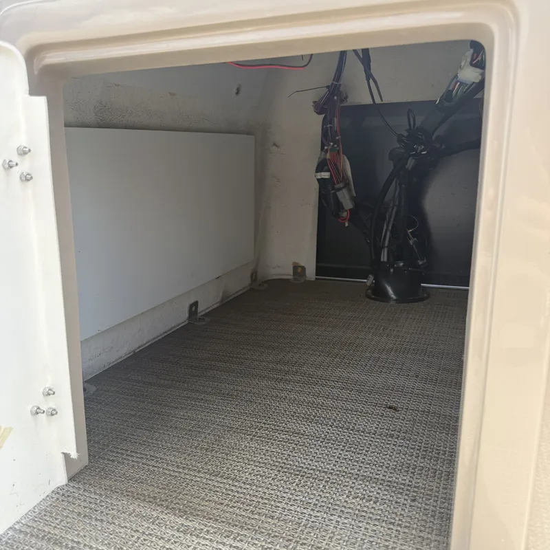 Slide: The Image of An empty storage compartment with carpeted floor and visible wiring on the back wall. - 28