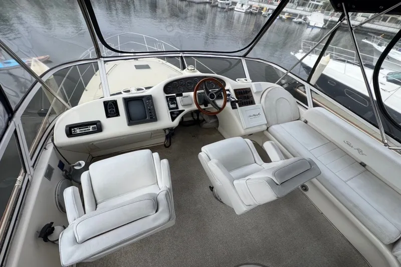 Slide: The Image of 1997 Sea Ray 420 Aft Cabin helm with white seating and wood-accented steering wheel. - 2